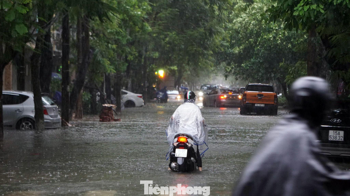 Nhiều người bất lực nhìn các phương tiện di chuyển qua phố ngập.