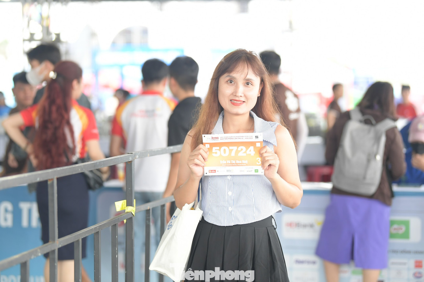 Một nữ VĐV khoe bib trước khi nhận race kit.