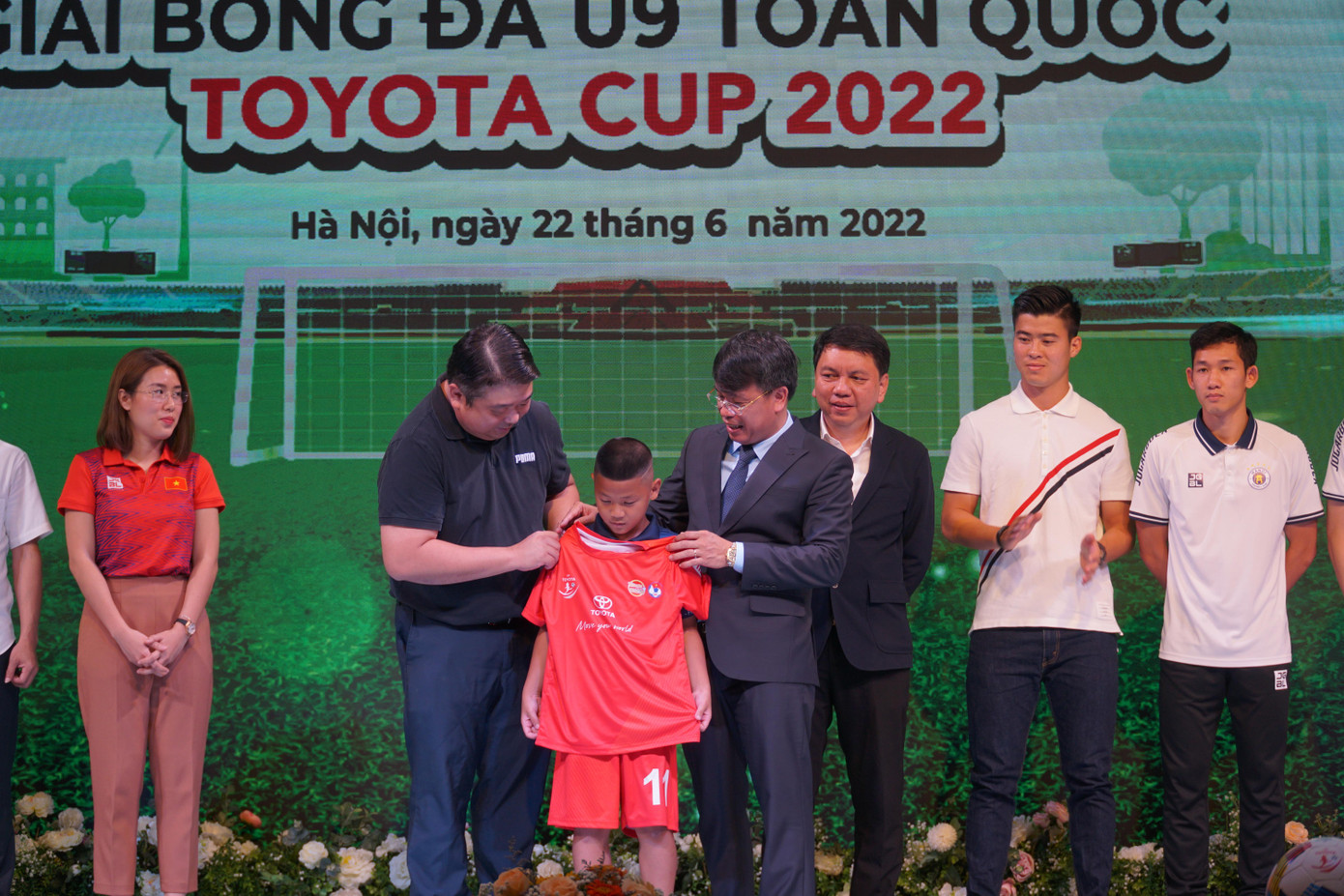 Đại diện nhà tài trợ Công ty Ô tô Toyota Việt Nam cùng nhà báo Nguyễn Phan Khuê, Tổng biên tập báo Thiếu niên Tiền Phong và Nhi Đồng, trao áo cho cầu thủ của H.Y.S Hà Nội. (Ảnh: Nguyễn Ngọc)