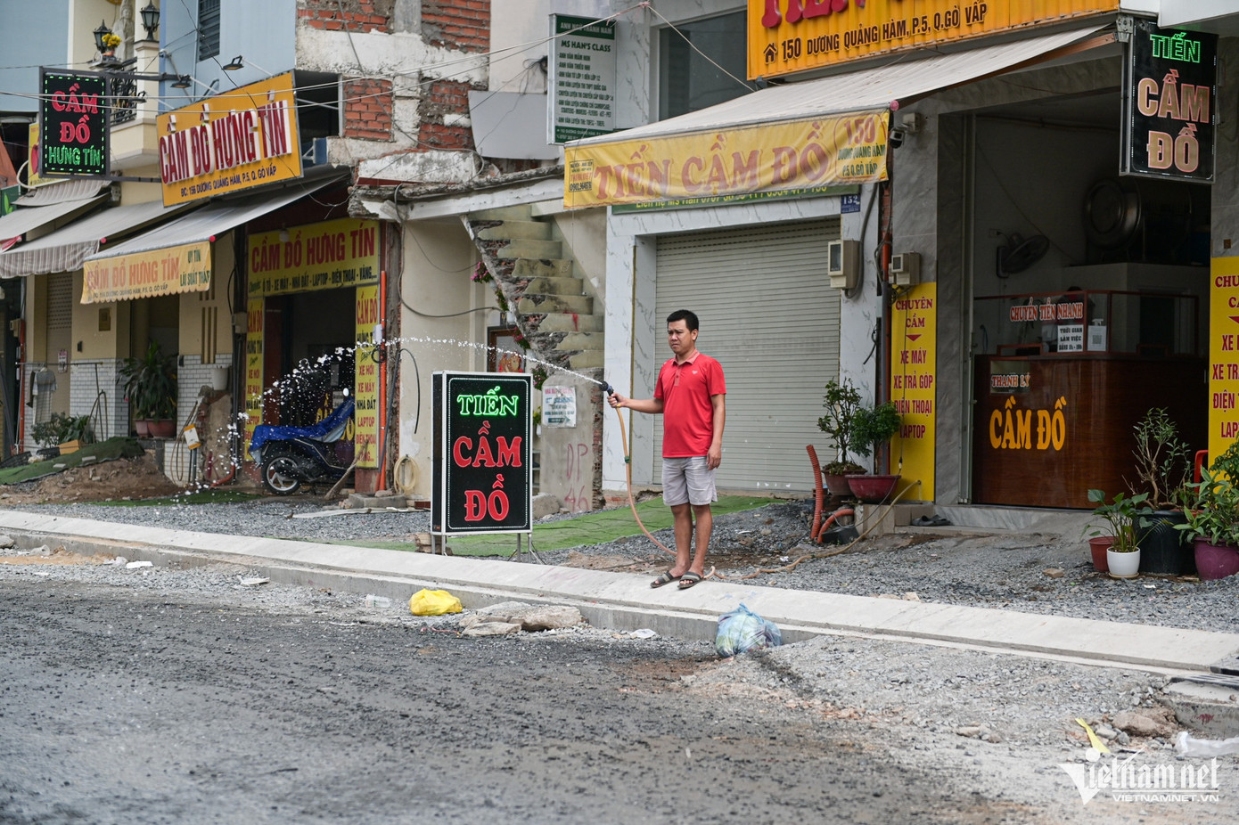 Người dân phải phun nước ra đường giảm bớt bụi khi nhiều phương tiện lớn đi qua đoạn đường chưa hoàn thiện.