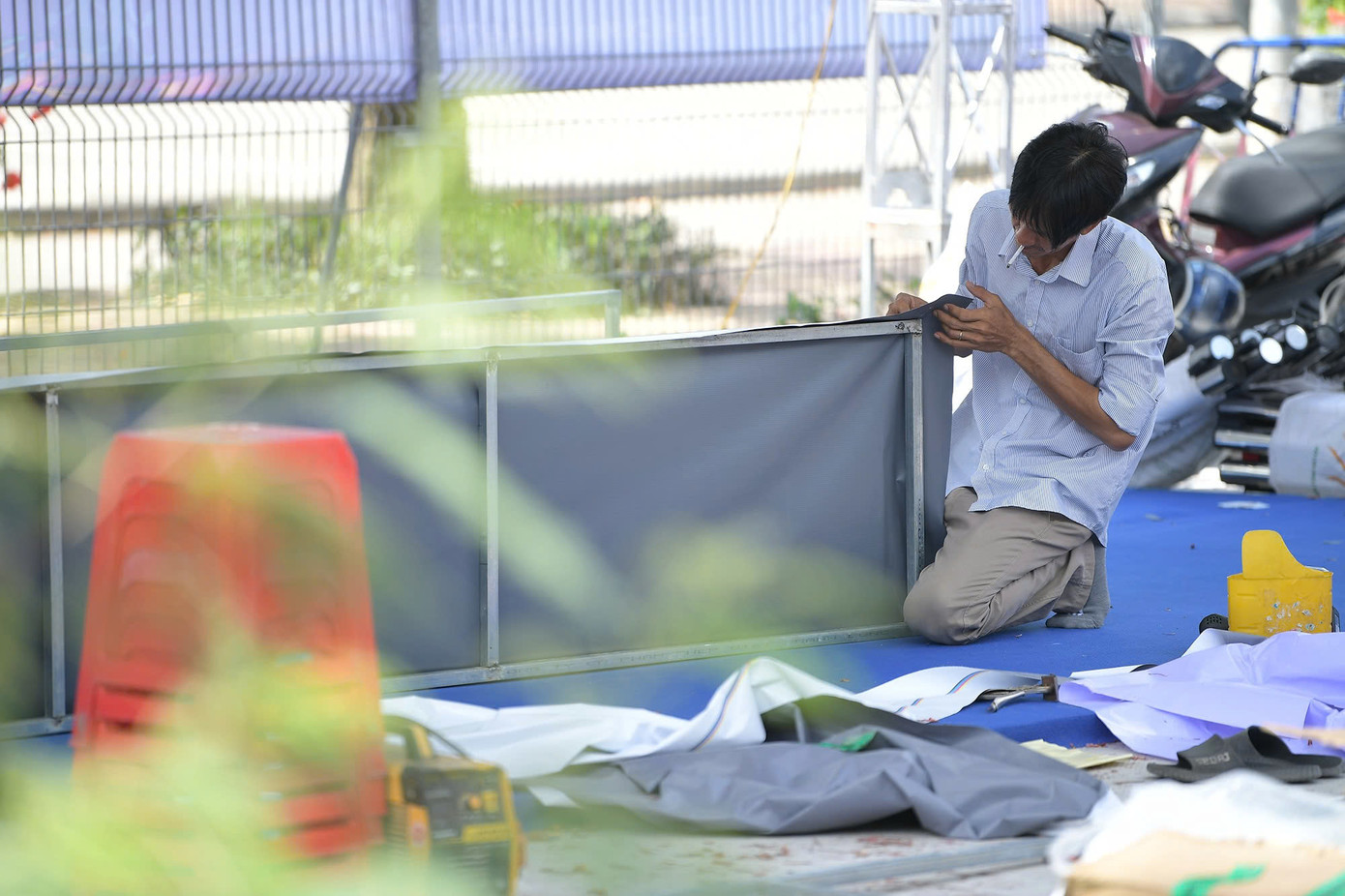 Bất chấp thời tiết, đội ngũ kỹ thuật lắp đặt các áp phích quảng bá giải một cách cẩn trọng.