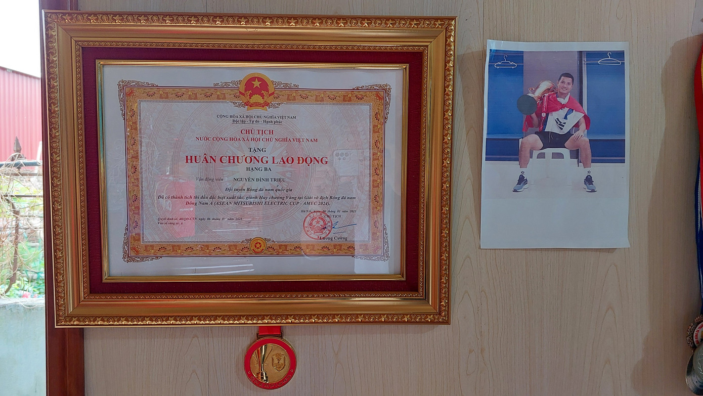 Bà Nhĩn khoe tấm Huân chương Lao động hạng ba được Chủ tịch nước trao tặng cho Đình Triệu, cùng các kỷ vật khác trong sự nghiệp của con trai. (Ảnh: Thanh Hải)