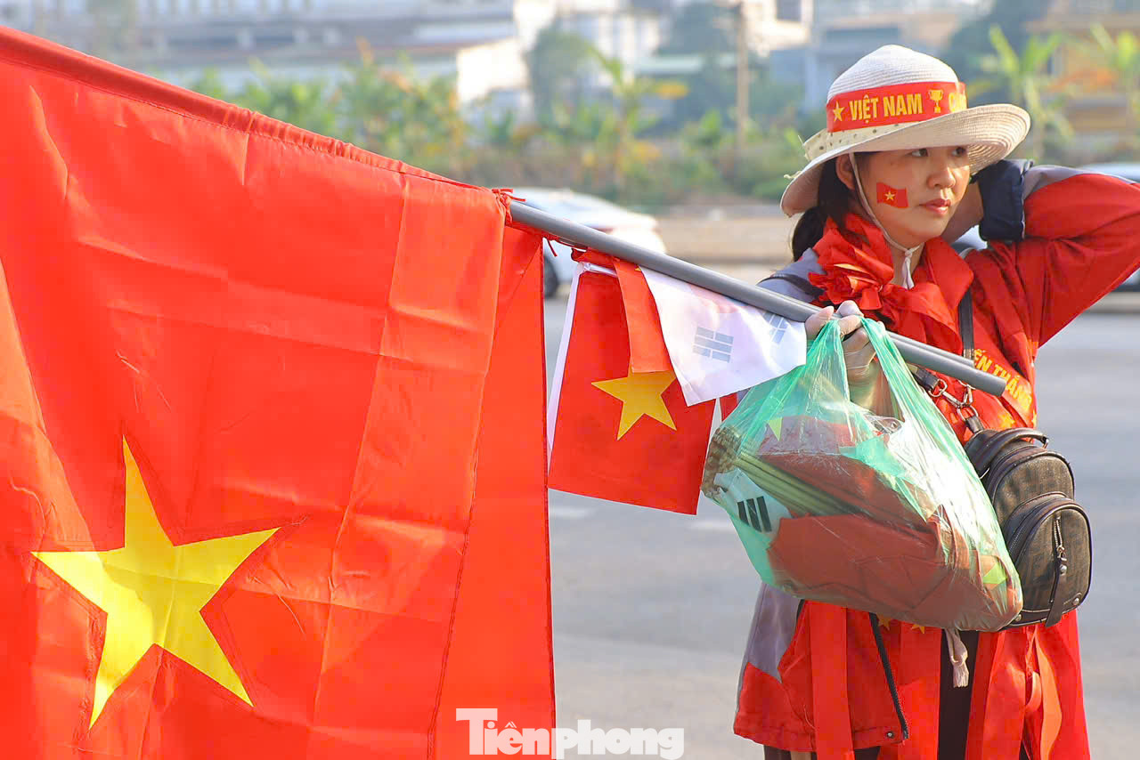 Khi các cổ động viên chưa đổ về, xung quanh sân vận động Việt Trì đã rực đỏ màu cờ, được tạo ra bởi những người bán đồ cổ vũ. Khi các cổ động viên chưa đổ về, xung quanh sân vận động Việt Trì đã rực đỏ màu cờ, được tạo ra bởi những người bán đồ cổ vũ.
