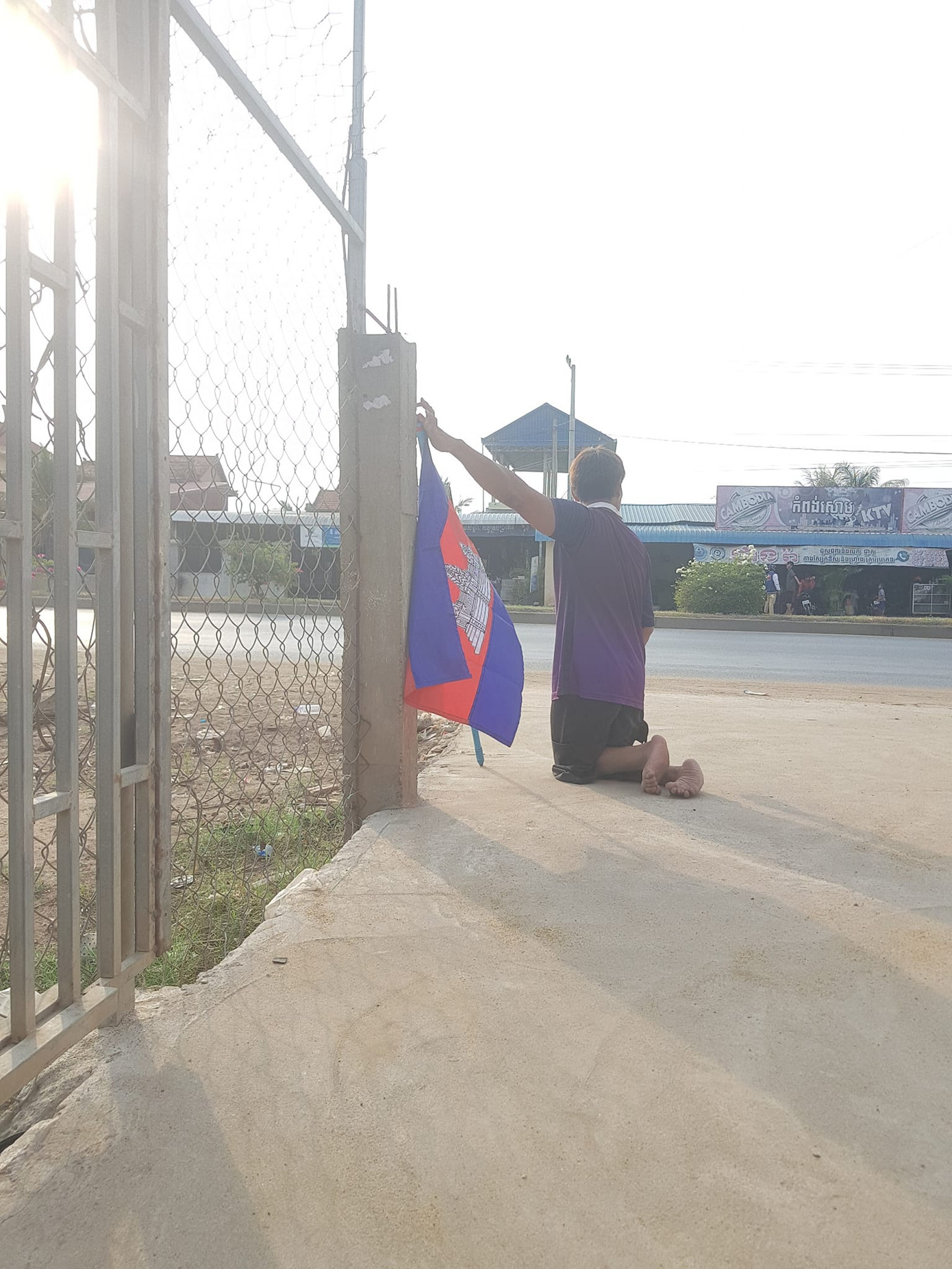 Chàng trai ở tỉnh Kandal cùng lá cờ Campuchia chờ đoàn rước đuốc SEA Games 32.