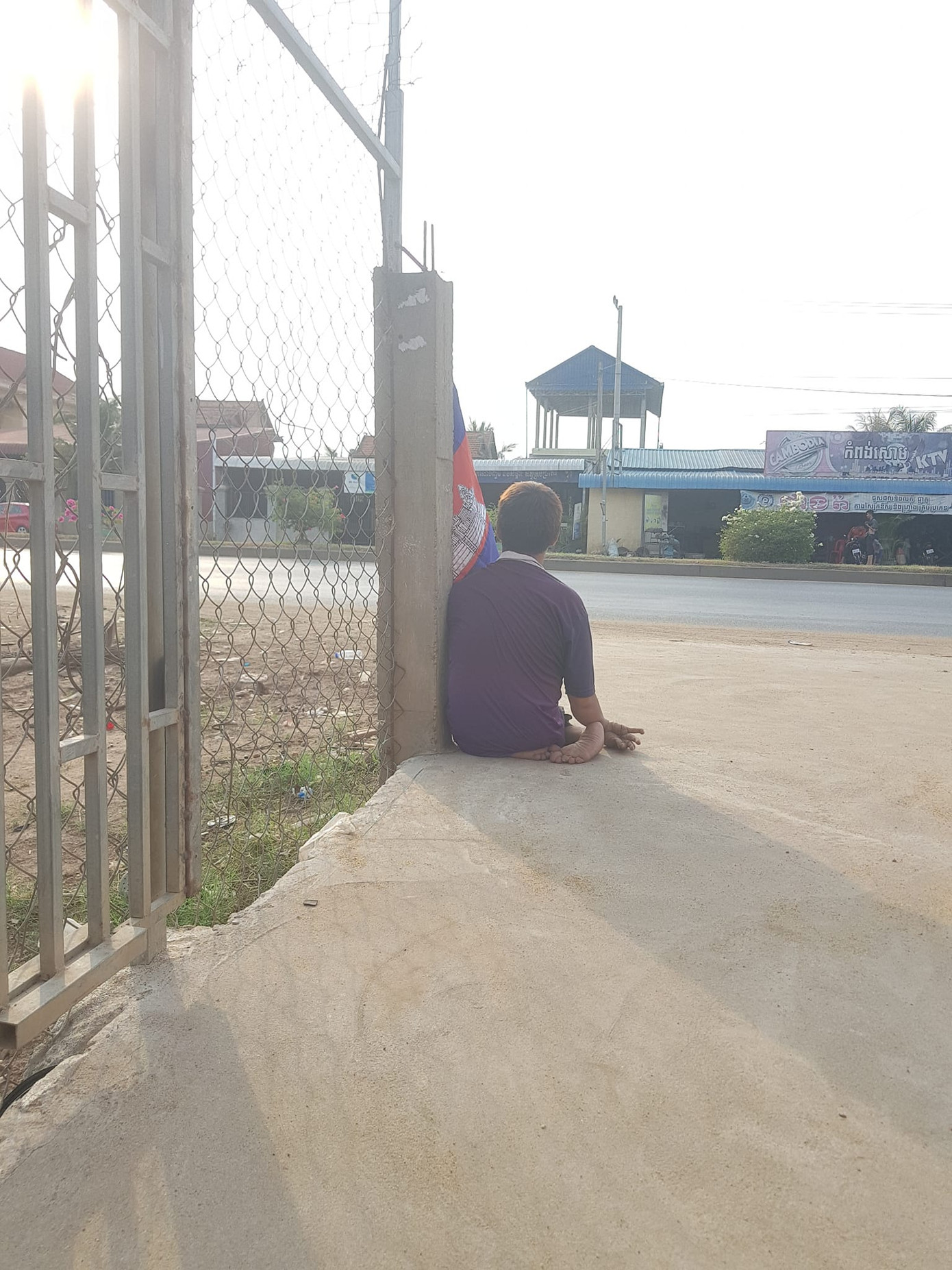 Chàng trai ở tỉnh Kandal cùng lá cờ Campuchia chờ đoàn rước đuốc SEA Games 32.