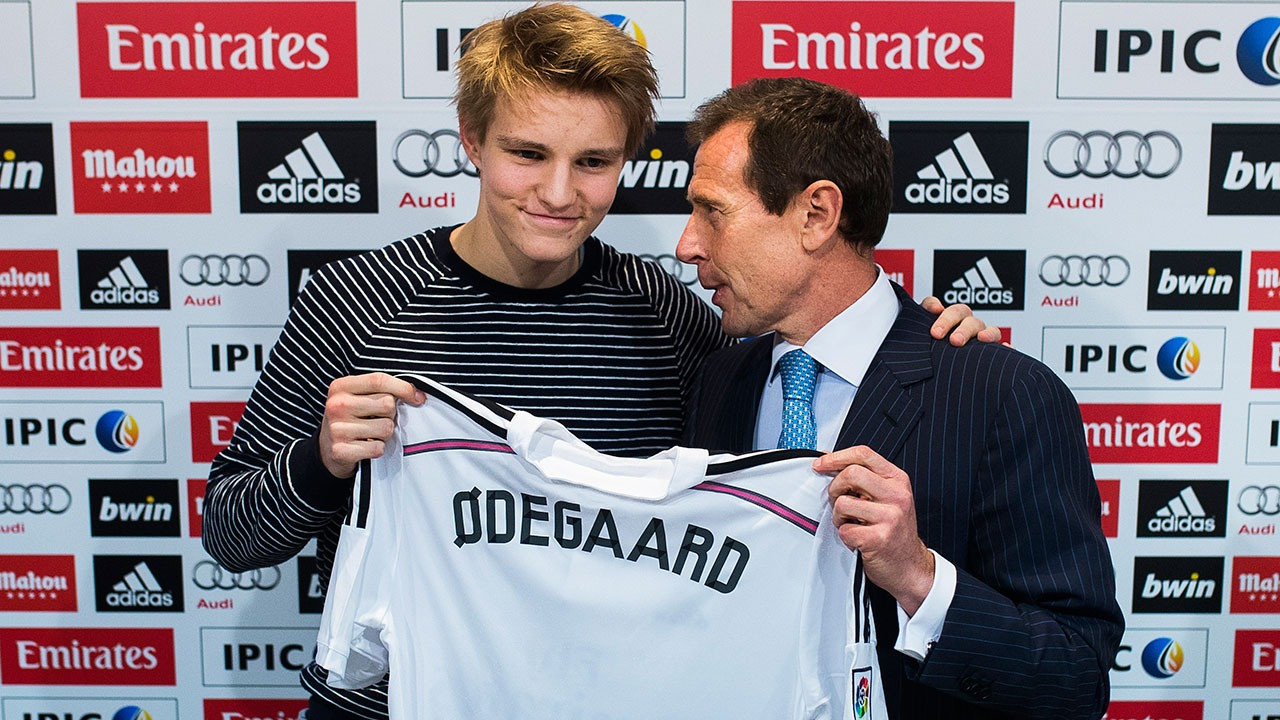 Odegaard nhận chiếc áo Real từ huyền thoại Emilio Butragueno trong buổi họp báo năm 2015.