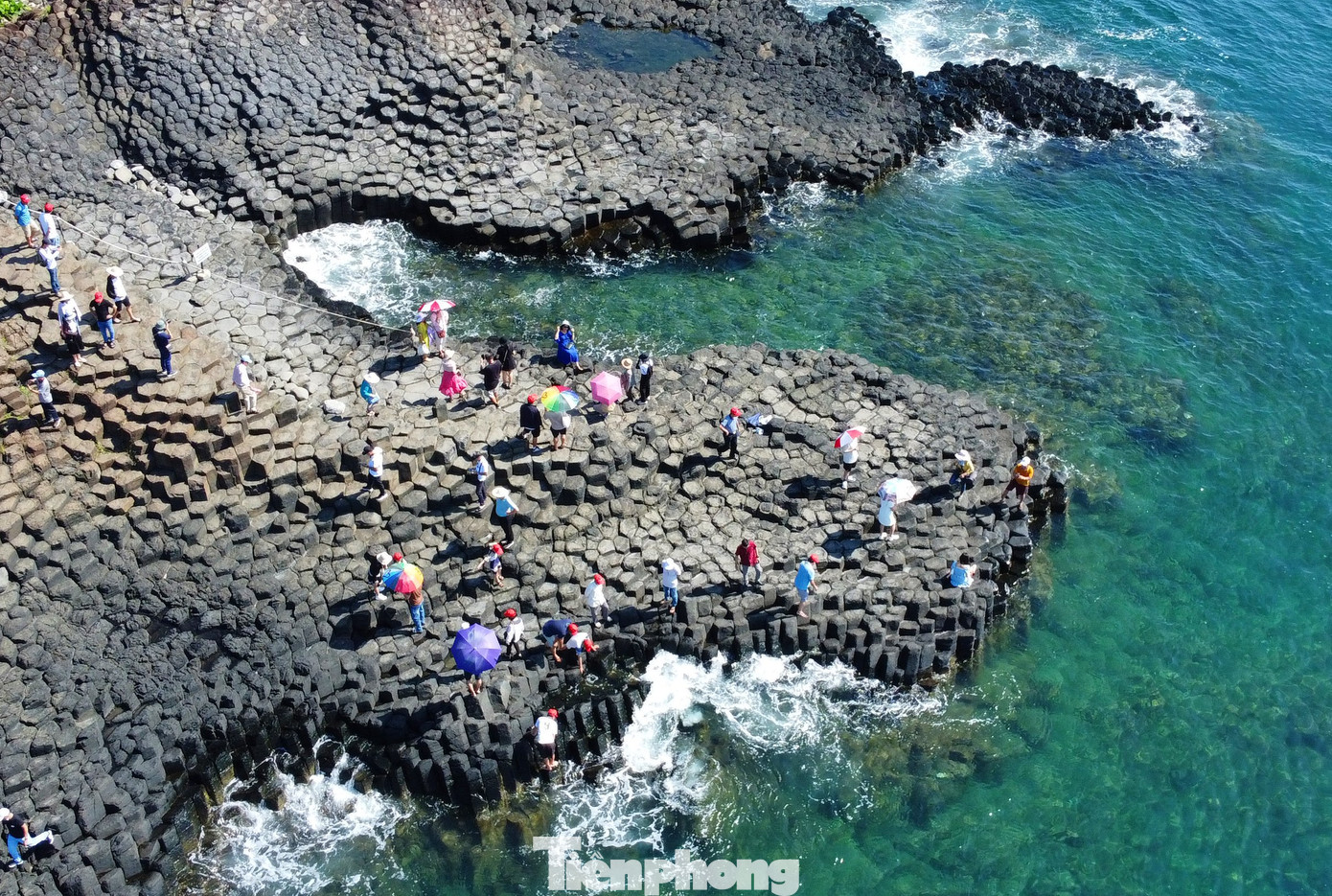 Những con sóng từ mặt biển xanh màu lục, khi va vào những khối đá đen tạo thành các cột sóng trắng xóa, một sự kết hợp tuyệt đẹp của màu sắc.