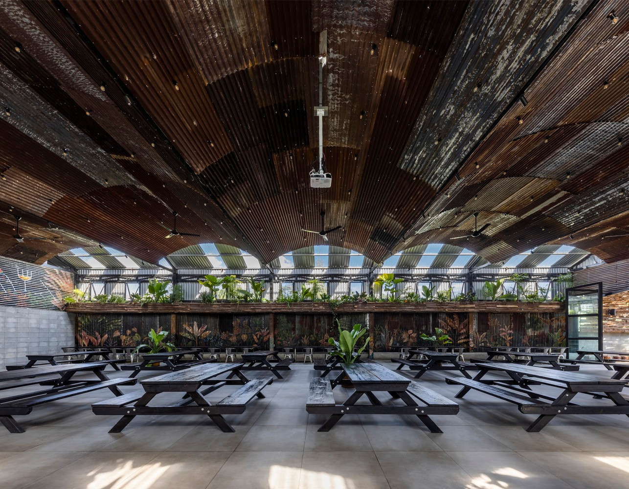 Khu vực ăn uống trong nhà được thiết kế với phần mái tôn cách nhiệt kết hợp hệ trần trang trí cũ kĩ, hệ thống phun sương ẩn nấp khéo léo trên mái và mảng cây cối được treo lên để giảm nóng đồng thời tăng cảm giác mới mẻ cho thực khách để tạo điểm thu hút riêng biệt cho khu vực này.