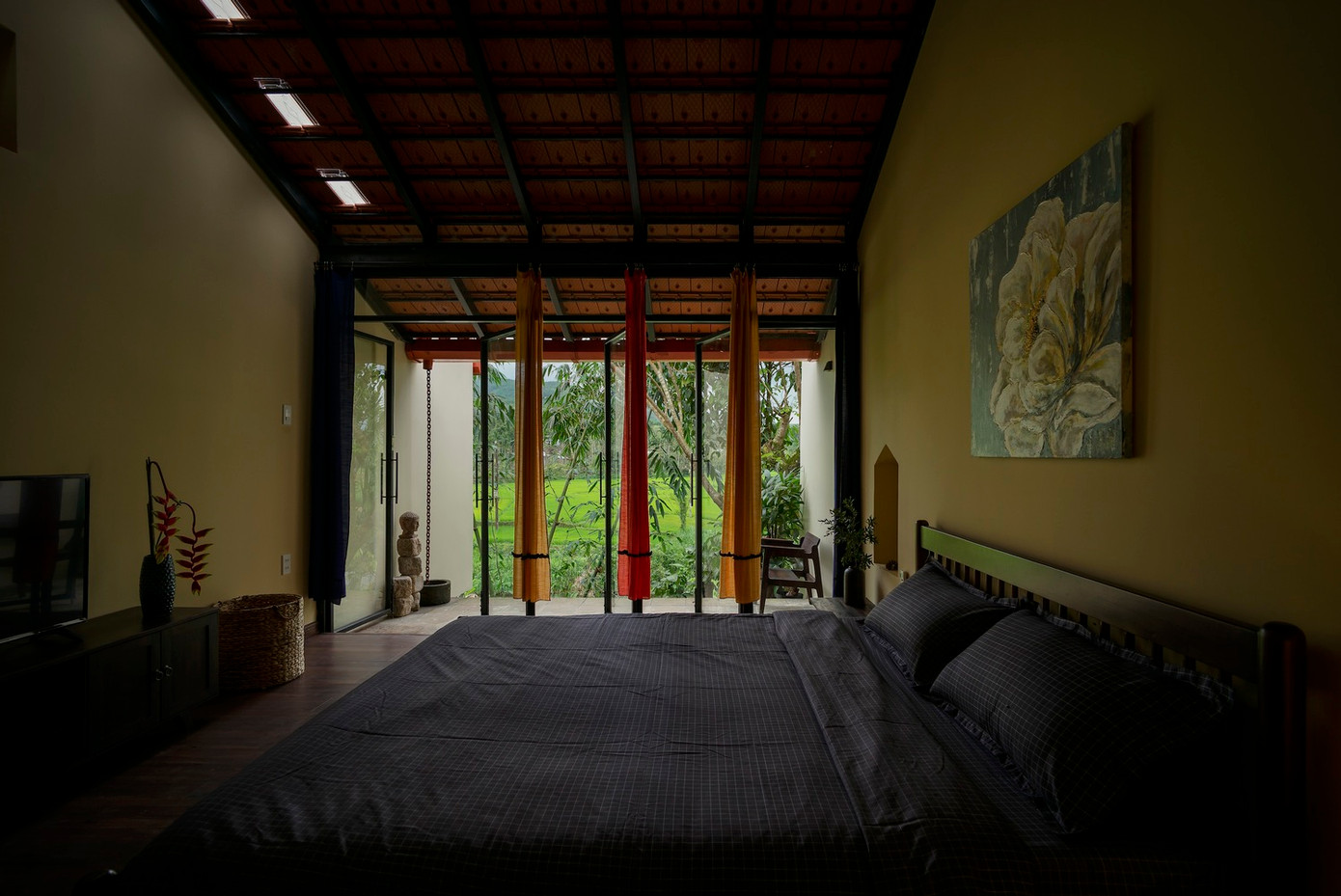 Các không gian chính tiếp cận trực tiếp với không gian ngoài trời thông qua các ô cửa và cửa sổ lớn, mang đến cảnh quan xanh tràn đầy sức sống và đón ánh sáng tự nhiên, cùng với khung cảnh nhìn ra cánh đồng lúa xanh và rừng cây tươi tốt.