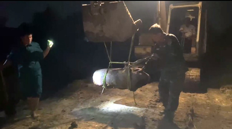 Quả bom được chuyển ra ngoài khu vực để đưa lên xe chuyển đi. Ảnh: Thành Trung