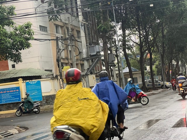 Người dân Bình Dương mặc áo mưa ra đường trong cơn mưa đầu mùa