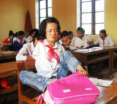 Thắm khéo léo dùng chân mở cặp và lấy sách ra học bài