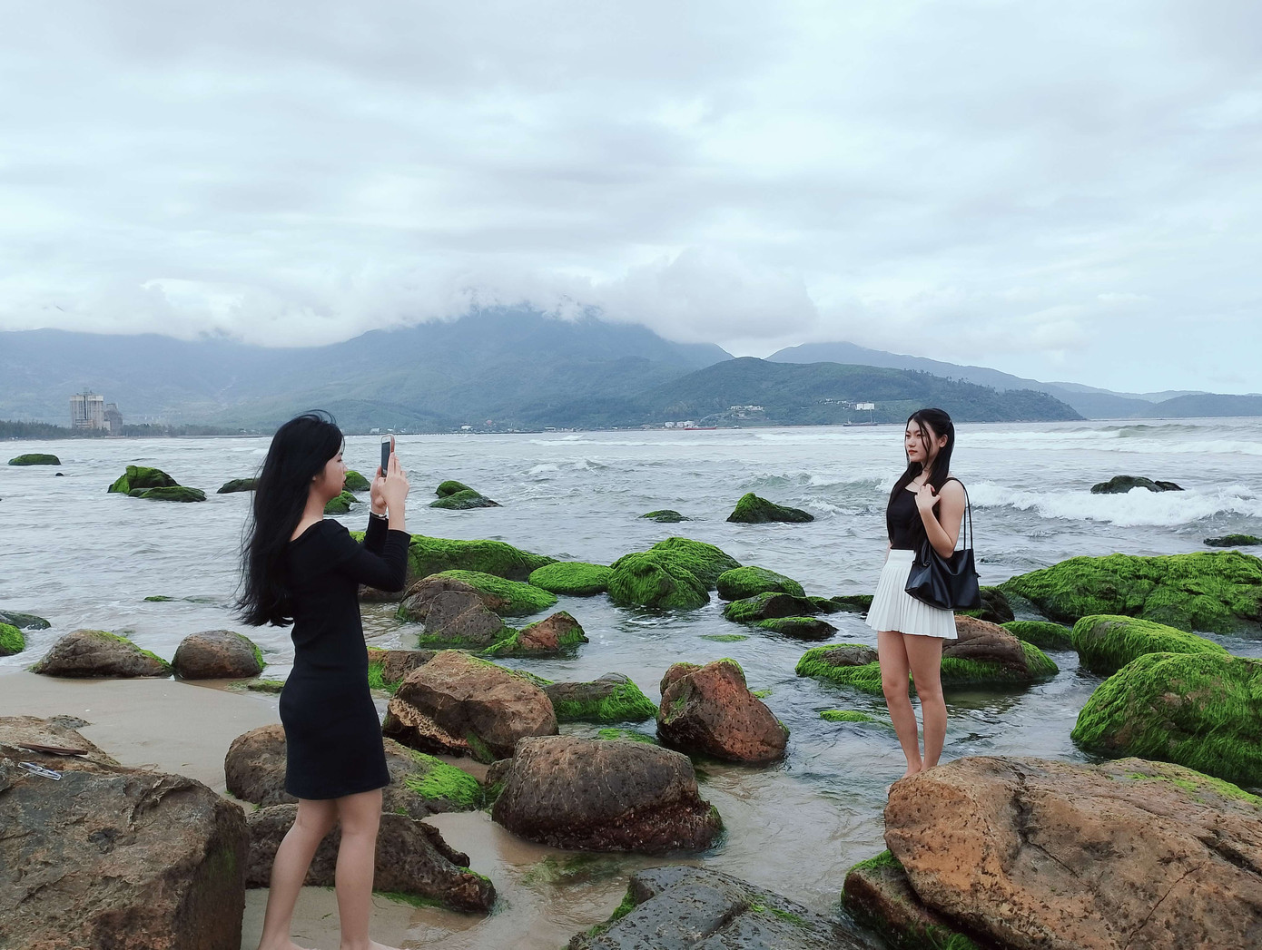 Bích Trâm (phải) "thả dáng" giữa làn sóng, bên những tảng đá phủ rêu xanh. Ảnh: Hữu Tùng Bích Trâm (phải) "thả dáng" giữa làn sóng, bên những tảng đá phủ rêu xanh. Ảnh: Hữu Tùng