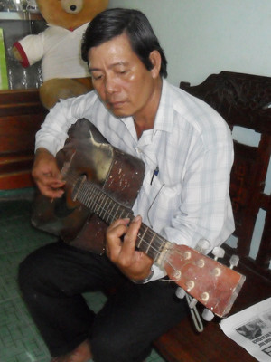 Ông Phạm Thanh Hùng ôm đàn khi vắng khách đi xe ôm. Ảnh: Hòa Hội