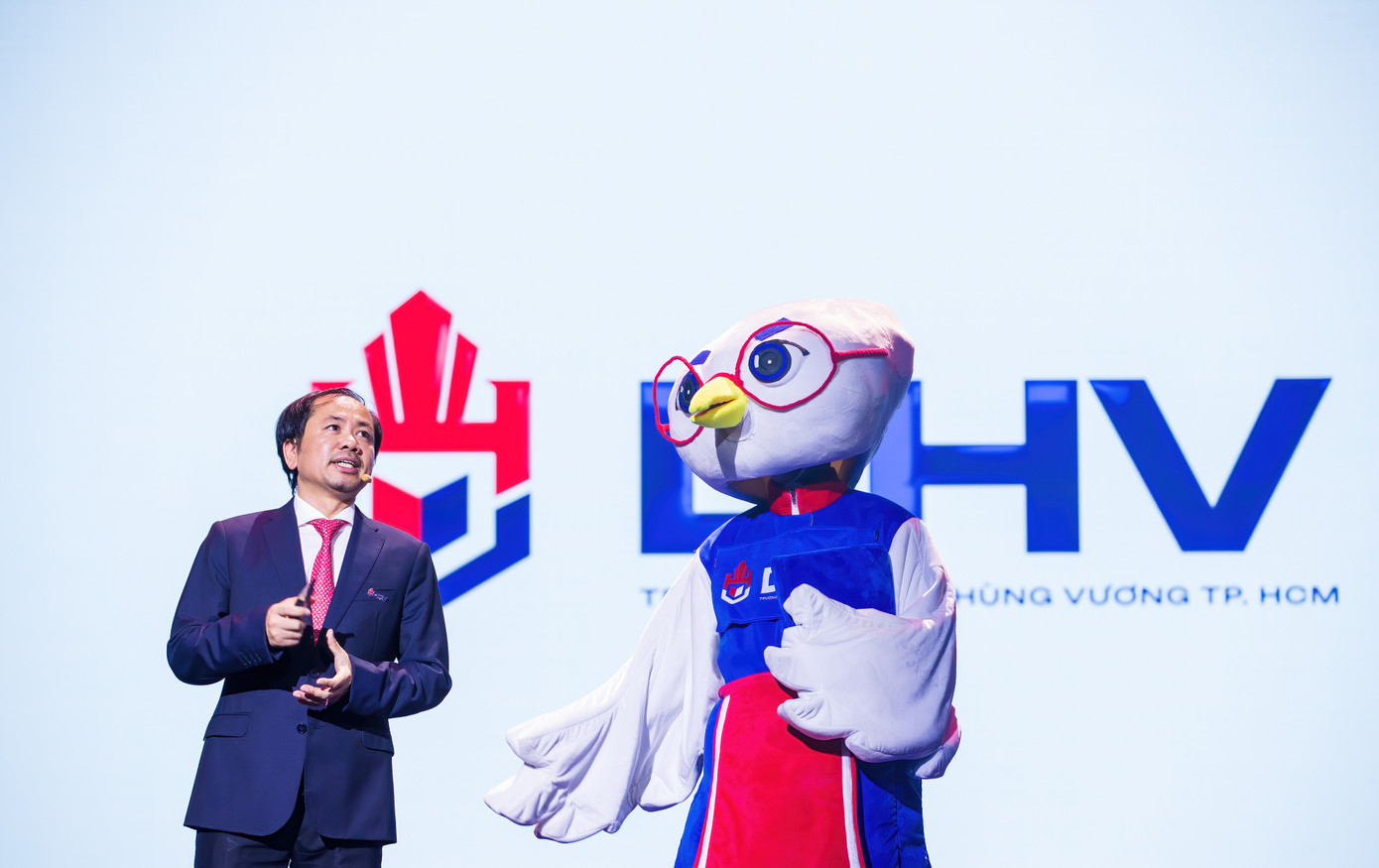 Linh vật là một chú cò với trang phục truyền thống thời Hùng Vương đang được Trường ĐH Hùng Vương kêu gọi sinh viên đặt tên