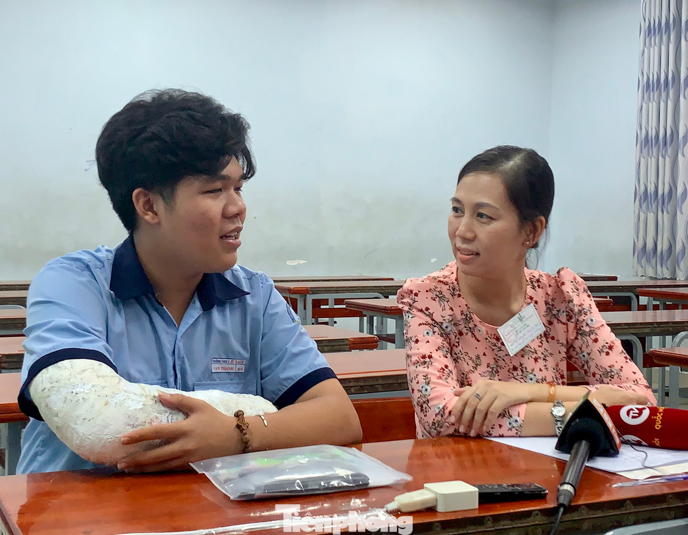 Hai cô trò trò chuyện với nhau ở phòng thi trước khi làm bài thi. Trên bàn có máy ghi âm, trước mặt cô trò là camera ghi hình và 1 giám thị ngồi ở trên quan sát (ảnh: Thùy Linh)