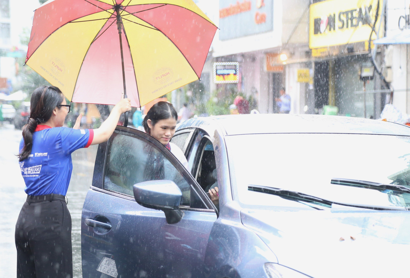 Thí sinh được tình nguyện viên che dù từ điểm thi ra xe