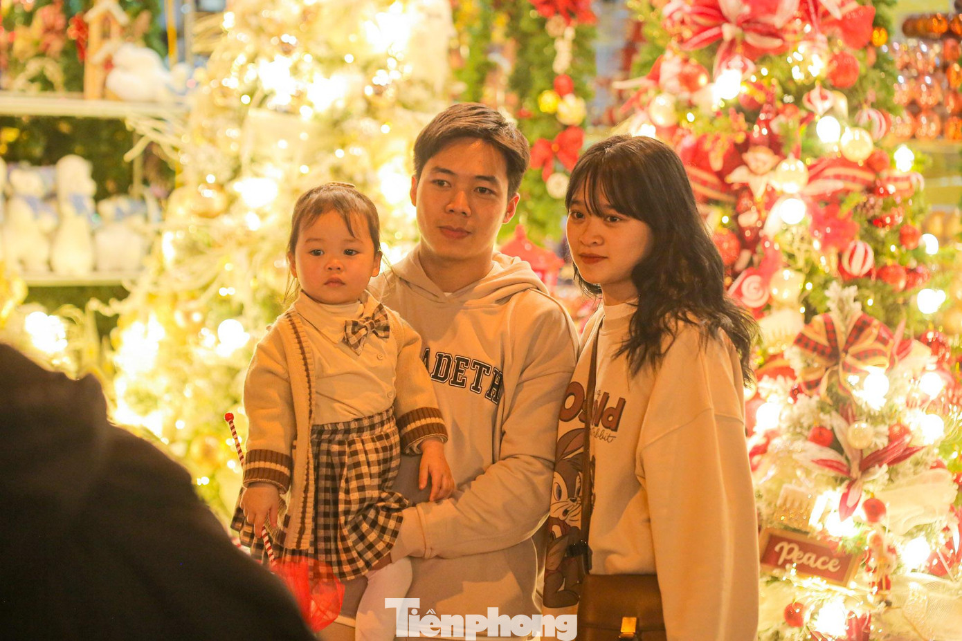 Một gia đình trẻ chụp ảnh bên cạnh cây thông Noel.