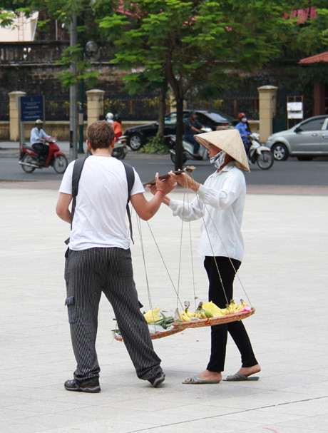 Một người phụ nữ bán hàng rong khác tiếp cận du khách, định đặt gánh hàng lên vai nhưng bị từ chối. Ảnh: Trường Phong