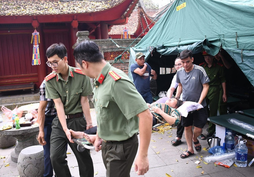 Cũng trong ngày 13/4, lực lượng công an làm nhiệm vụ tại Đền Hạ phát hiện ông Võ Văn Thống (55 tuổi, thành phố Rạch Giá, Kiên Giang) trên đường từ cổng chính lên Đền Hạ không may bị ngất. Các chiến sĩ công an trực chốt tại đây đã kịp thời sơ cứu rồi đưa ông Thống về lán để chăm sóc. Đến 12h trưa, sức khỏe của ông Thống đã ổn định để cùng người thân trở về gia đình. Công an dùng cáng đưa người dân bị ngất xỉu về lán để lực lượng y tế sơ cứu, cấp cứu (Ảnh: Công an Phú Thọ).