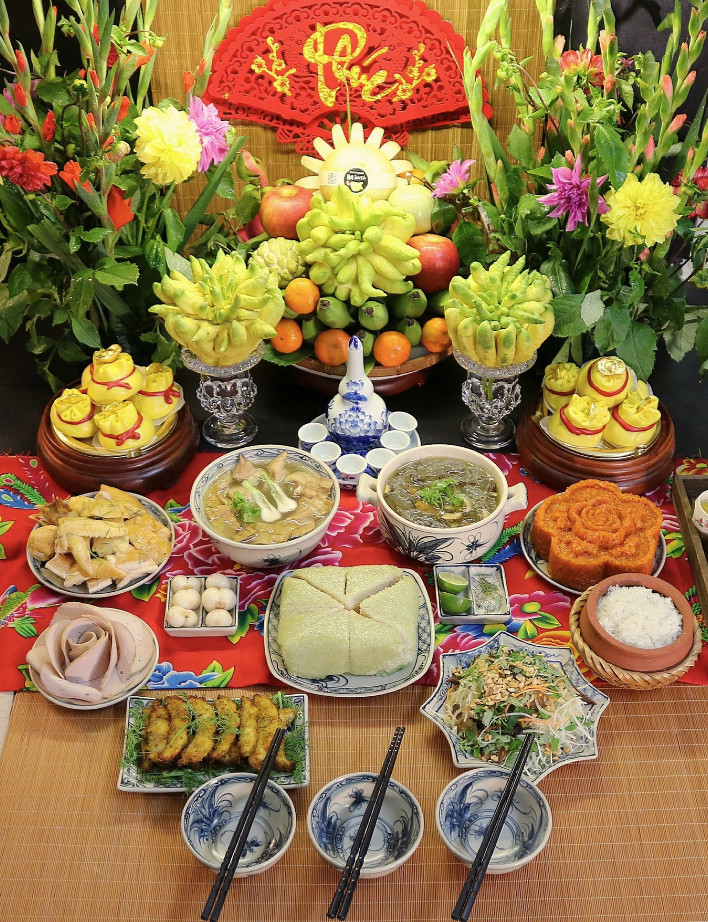 Mâm cúng rằm tháng Chạp với gà luộc, chả cá Lã Vọng, nộm đu đủ bò khô, xôi gấc, bánh chưng, dưa hành, bánh bao túi tiền, canh măng móng giò, canh miến lòng gà, cơm gạo.