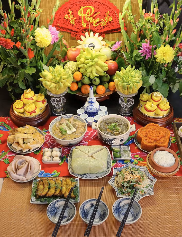Mâm cúng rằm tháng Chạp với gà luộc, chả cá Lã Vọng, nộm đu đủ bò khô, xôi gấc, bánh chưng, dưa hành, bánh bao túi tiền, canh măng móng giò, canh miến lòng gà, cơm gạo.