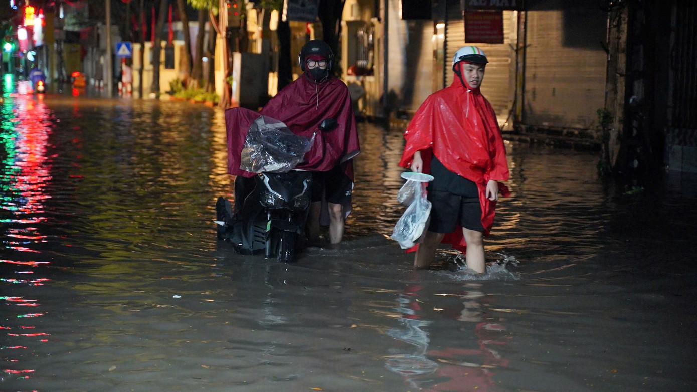 Người dân bì bõm dắt xe máy qua đoạn ngập nước Người dân bì bõm dắt xe máy qua đoạn ngập nước