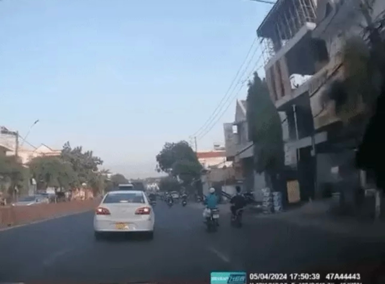 Hình ảnh người phụ nữ đi xe máy bị thanh sắt công trình rơi trúng đầu (Ảnh: Cắt từ clip). Hình ảnh người phụ nữ đi xe máy bị thanh sắt công trình rơi trúng đầu (Ảnh: Cắt từ clip).