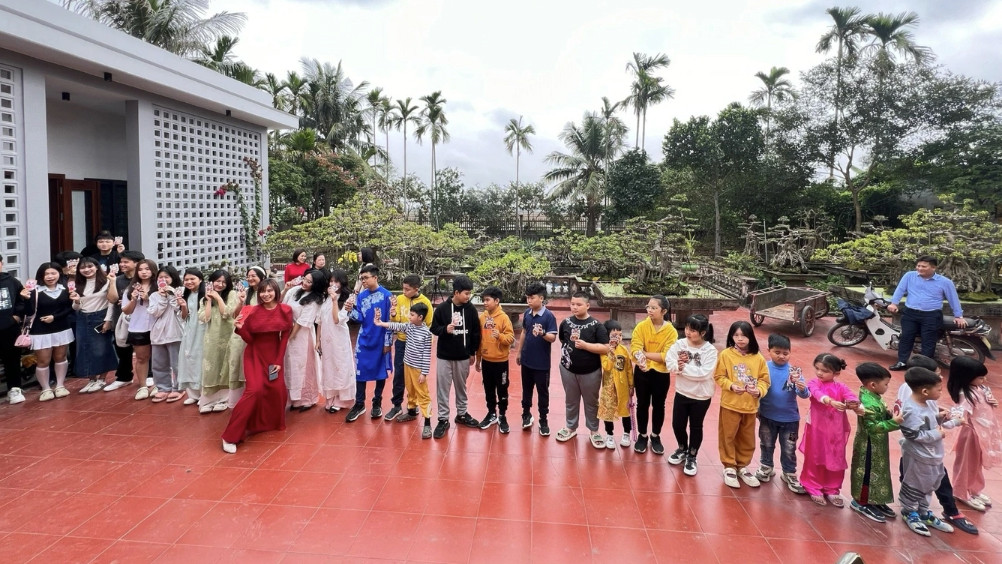 Bùi Phương (áo dài đỏ) chụp ảnh cùng các cháu của mình sau khi phát lì xì mừng tuổi (Ảnh: Nhân vật cung cấp).