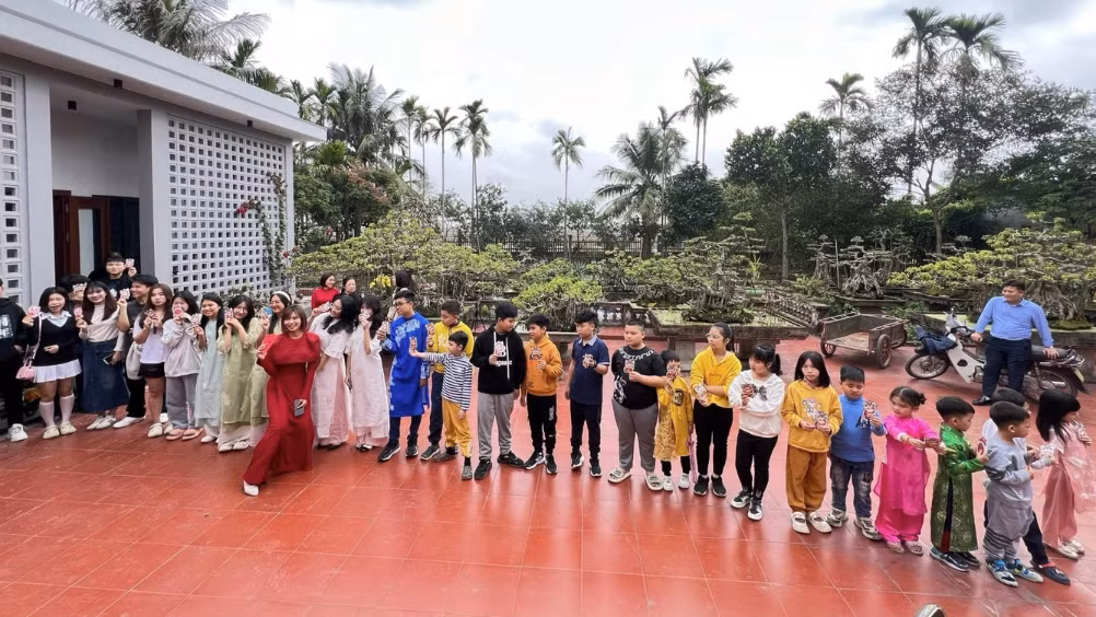 Bùi Phương (áo dài đỏ) chụp ảnh cùng các cháu của mình sau khi phát lì xì mừng tuổi (Ảnh: Nhân vật cung cấp).