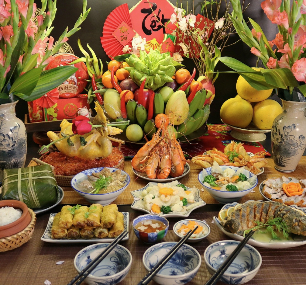 Mâm cỗ mùng 1 tháng Chạp gồm gà luộc cánh tiên, xôi gấc, cá quả sốt cam, tôm càng xanh hấp sả bia, bánh tôm Hồ Tây, nem rán truyền thống, bóng xào thập cẩm, thịt quay giòn bì, canh măng móng giò, canh bóng thả, bánh chưng, cơm gạo.