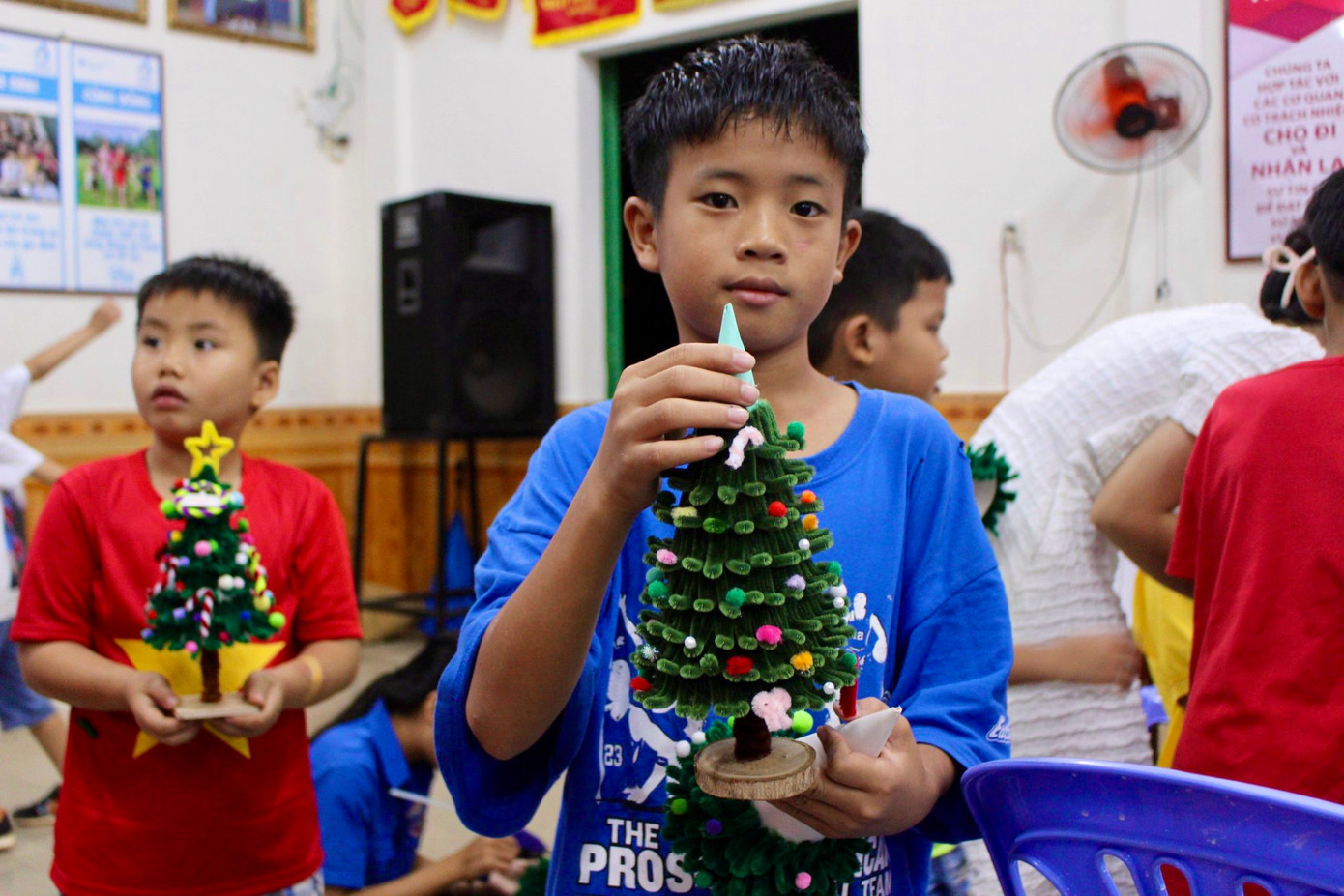 Em Lê Văn Quý (10 tuổi) tự hào khoe thành phẩm sau hơn 1 tiếng thực hiện: “Lúc mới bắt đầu làm em còn lóng ngóng nhưng sau khi các chị hướng dẫn em đã quen dần và tự làm được cây thông để đem về trưng tại góc học tập”.