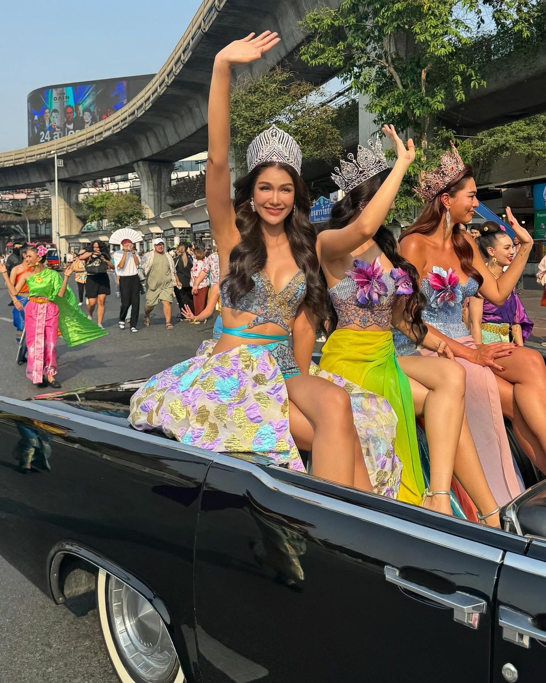 Hoa hậu Hoàn vũ Thái Lan 2021 Anchilee Scott-Kemmis, Hoa hậu Hoàn vũ Thái Lan 2015 Aniporn Chalermburanawong, Hoa hậu Hoàn vũ Thái Lan 2016 Namtan Chalita Suansane diện trang phục rực rỡ, nổi bật khi ngồi trên xe diễu hành.