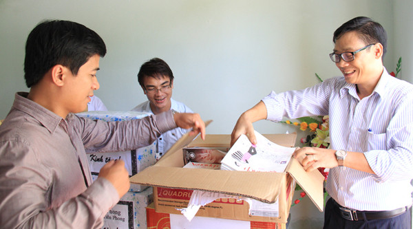 Phó Tổng biên tập Tô Quang Nam (phải) cùng phóng viên báo Tiền Phong mở hộp sách để tặng cho các cháu nhỏ. Ảnh: Trường Phong