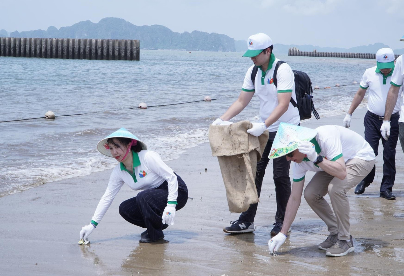 Thứ trưởng Bộ Ngoại giao Lê Thị Thu Hằng (người ngồi đầu bên trái) cùng các đại biểu thu gom rác trên bãi biển.