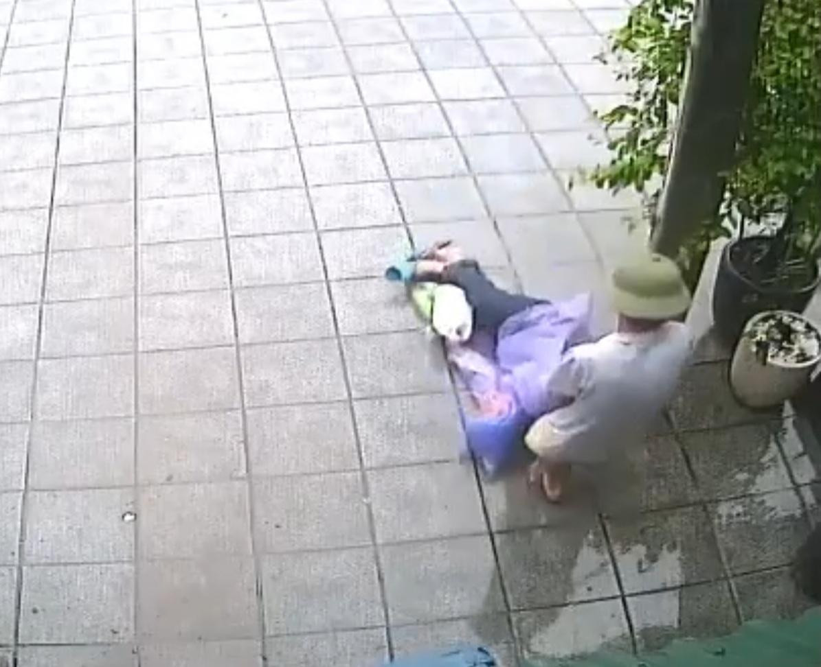 Người đàn ông đội mũ cối kéo lê người đàn ông bất tỉnh rồi vứt bỏ bên vỉa hè dưới trời mưa. Ảnh cắt từ clip