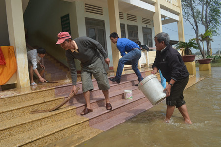 Hiệu trưởng Trường Tiểu học Cát Chánh cũng xắn quần dội nước. ảnh Việt Hương
