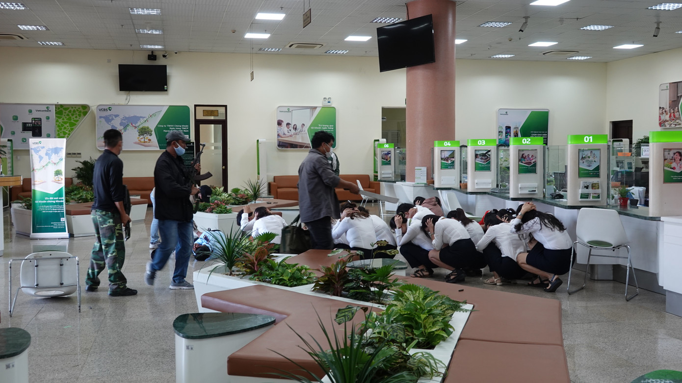 Các "tên cướp" trước quầy giao dịch ngân hàng, khống chế 12 “con tin” đưa lên tầng 3 để cố thủ, đòi yêu sách.