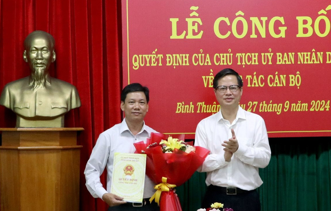 Ông Đoàn Anh Dũng - Chủ tịch UBND tỉnh Bình Thuận, trao quyết định, tặng hoa chúc mừng ông Đỗ Văn Chung. Ảnh: Báo Bình Thuận.