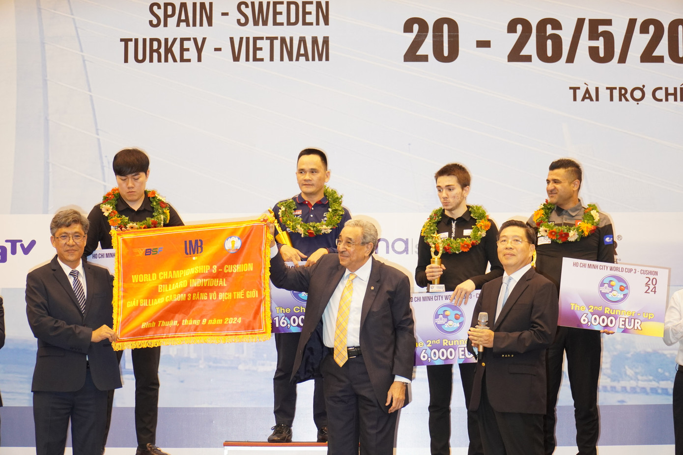 Ông Nguyễn Minh - Phó Chủ tịch UBND tỉnh Bình Thuận (bìa trái) tiếp nhận cờ đăng cai từ ông Farouk Barki - Chủ tịch Liên đoàn Billard Carom Thế giới (UMB). Ảnh: Báo Bình Thuận. Ông Nguyễn Minh - Phó Chủ tịch UBND tỉnh Bình Thuận (bìa trái) tiếp nhận cờ đăng cai từ ông Farouk Barki - Chủ tịch Liên đoàn Billard Carom Thế giới (UMB). Ảnh: Báo Bình Thuận.