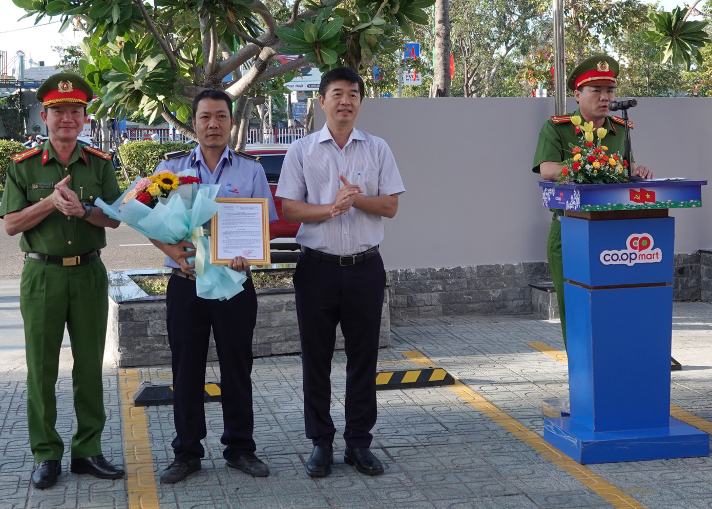 Ông Phan Nguyễn Hoàng Tân - Chủ tịch UBND TP. Phan Thiết và thượng tá Trần Long Khánh - Trưởng Công an TP. Phan Thiết trao quyết định và tặng hoa cho anh Định.