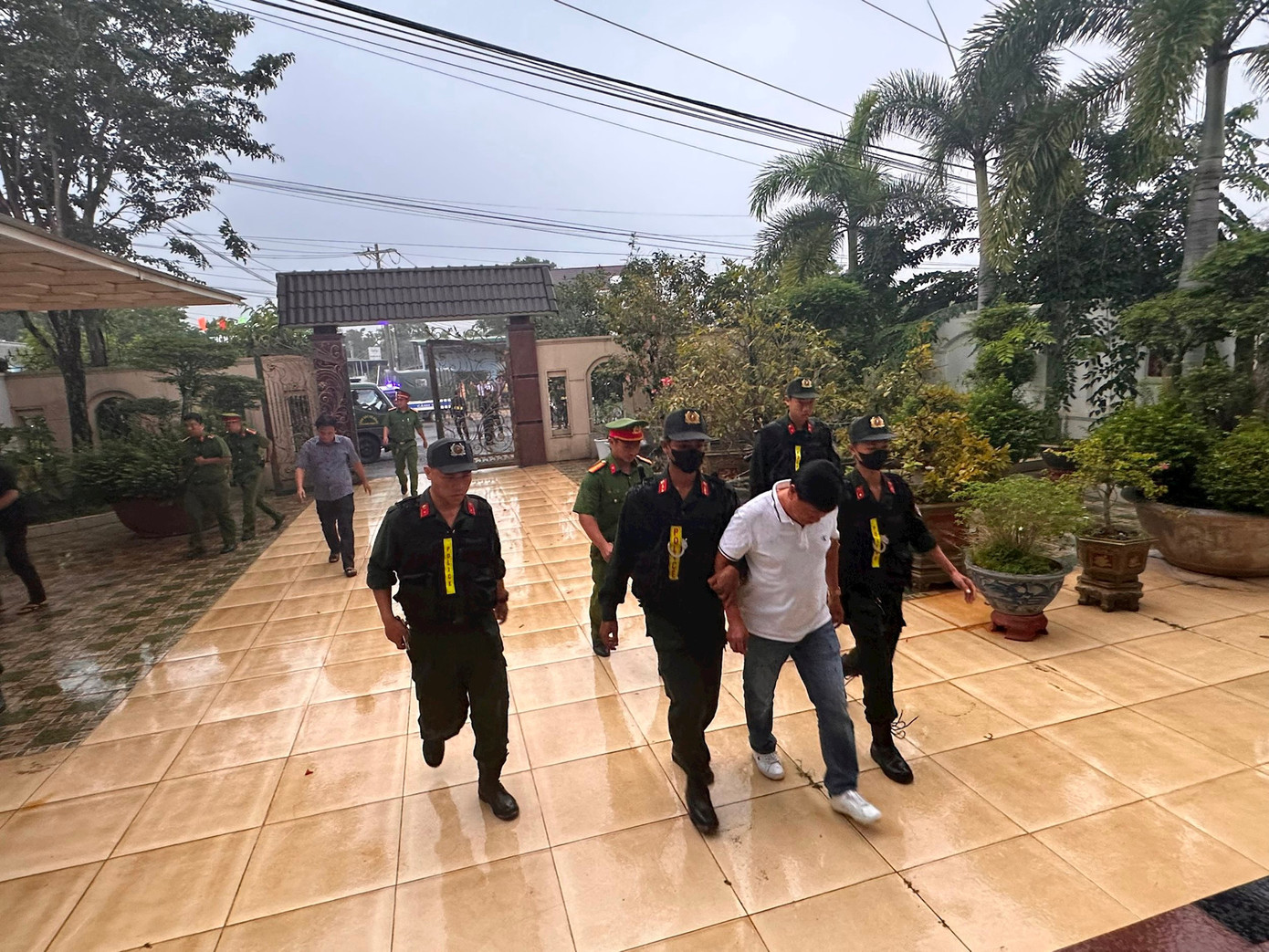 Lực lượng chức năng đưa Trần Văn Thuận về nhà để tiến hành khám xét. Ảnh: Báo Bình Thuận.