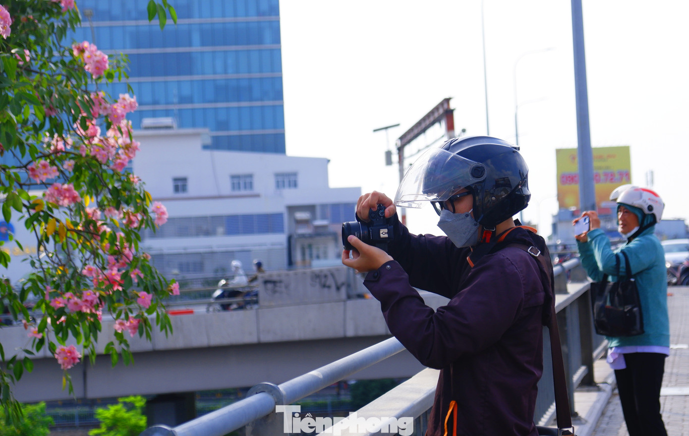 Một số người dân tranh thủ lưu giữ khoảnh khắc đẹp của hàng hoa kèn hồng trên đường Võ Văn Kiệt.