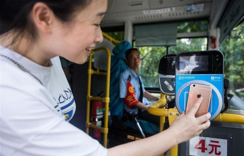 Một hành khách dùng ứng dụng Alipay để thanh toán trên chuyến xe buýt ở tỉnh Chiết Giang ngày 16/8/2016. Ảnh: Xinhua