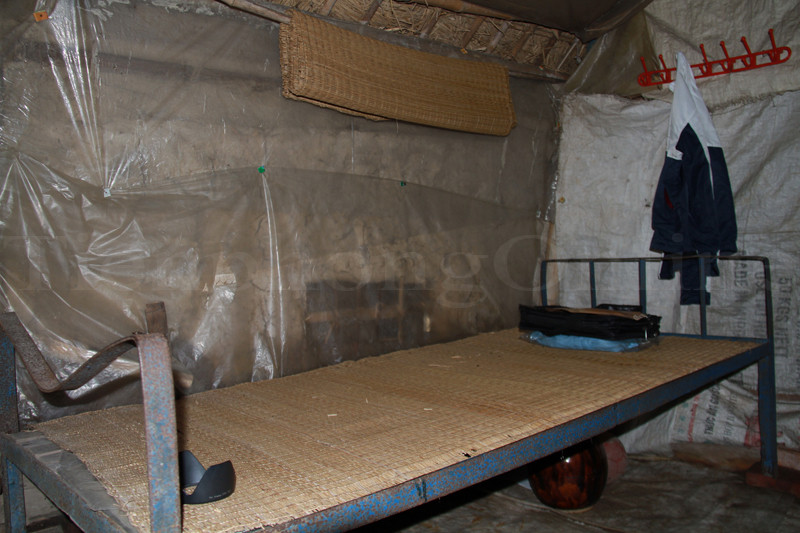 Chiếc giường sắt chiếm gần trọn căn nhà được để ngay cạnh bàn học của Đức. Ảnh: Trường Phong