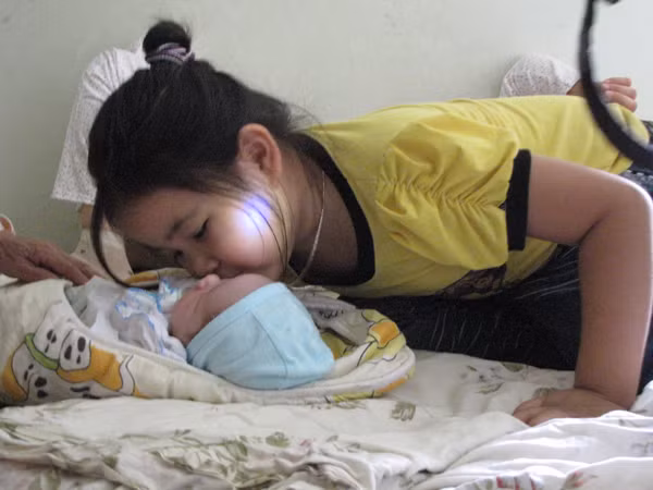 Cháu Ngân - con lớn anh Chiều lao vào thơm cháu Trường. Ảnh: Trường Phong