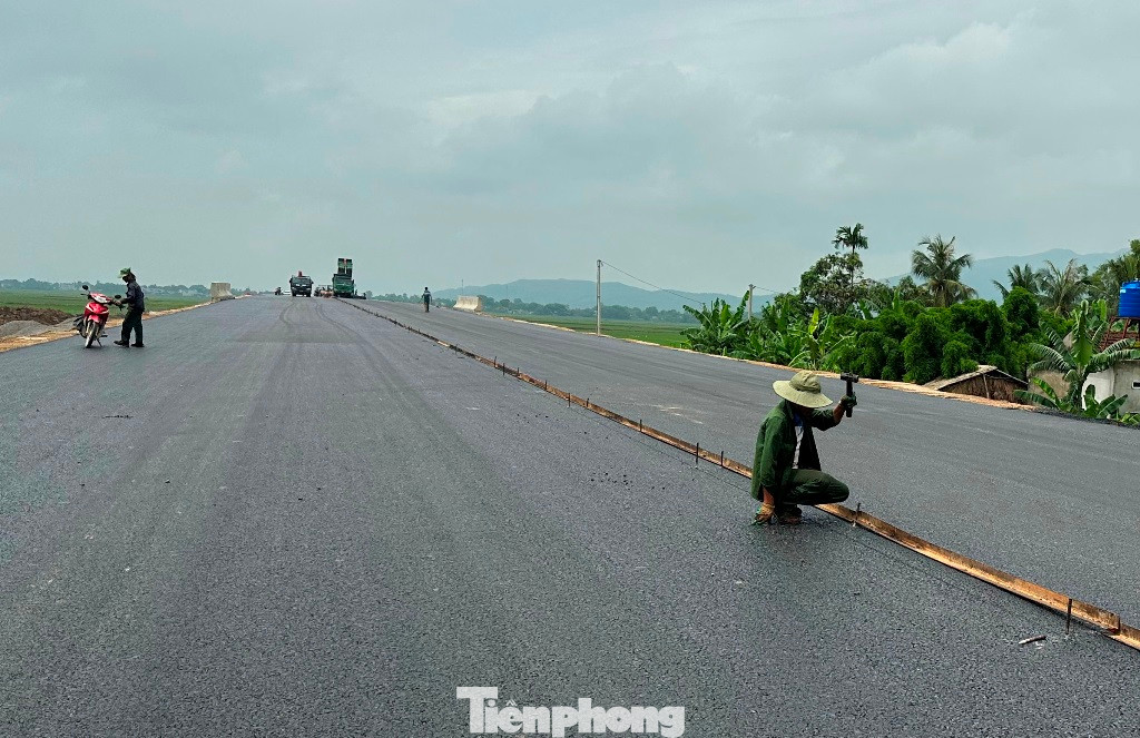 Công nhân thi công đang chia đôi làn đường để thảm lớp nhựa cuối cùng tại gói thầu XL01 đoạn dự án qua huyện Nông Cống, Thanh Hóa.