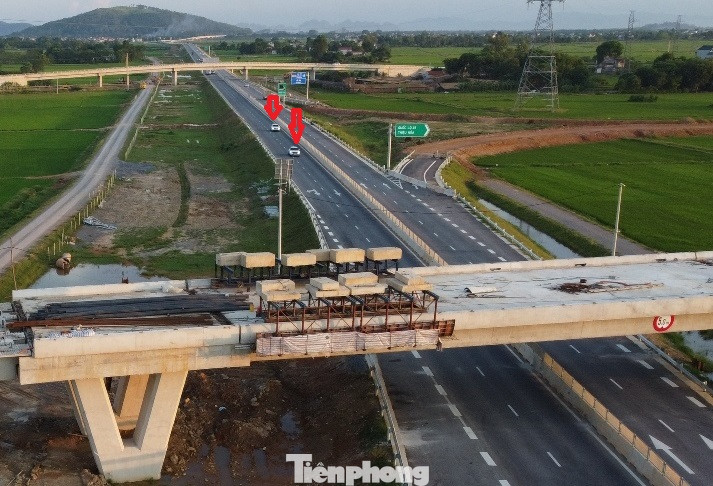 Cầu vượt cao tốc tại nút giao trên đang là công trường ngổn ngang, các phiến bê tông nặng để trên giàn giáo đã lâu ngày, bên dưới là xe ô tô lưu thông với tốc độ 60 - 80km/h