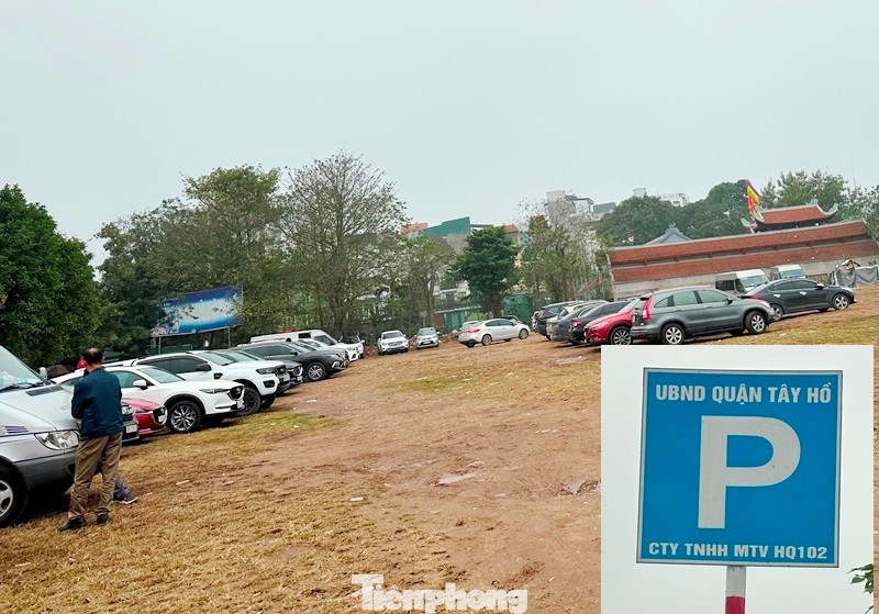 Tại bãi đất trống rộng lớn ven hồ Tây, có sức chứa cả nghìn ô tô, xe máy mỗi giờ được UBND quận Tây Hồ cấp phép cho Cty TNHH MTV HQ102 cắm biển (ảnh nhỏ) trông giữ xe, phục vụ người dân vào phủ.
