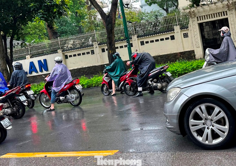 Người dân đi xe máy mệt mỏi đứng chờ nước rút để qua nhiều khu vực nước ngập.